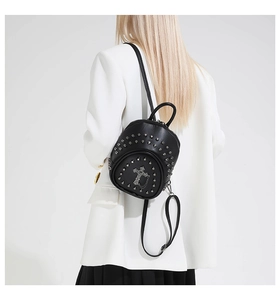 Détail d'un mini sac à dos gothique avec rivets argentés et croix porté par un mannequin