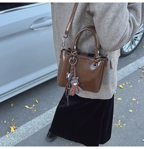 Borsa a secchiello in pelle cerata marrone con ciondolo a orsetto in look da strada