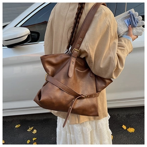 Close-up of vintage dark brown leather tote bag with adjustable strap in street style view