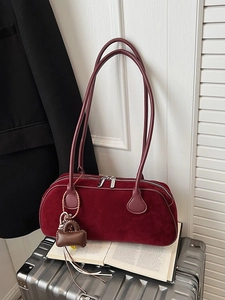 Vintage burgundy suede baguette bag with long strap and fringe detail on metallic suitcase
