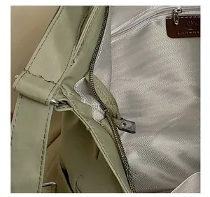 Detail view of the green nylon bag showing a smooth metal zipper and herringbone lining