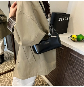 Detail of black glossy patent leather shoulder bag with silver sphere charm decoration