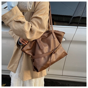 Detail of vintage large brown tote bag with leather texture and decorative buckle detail