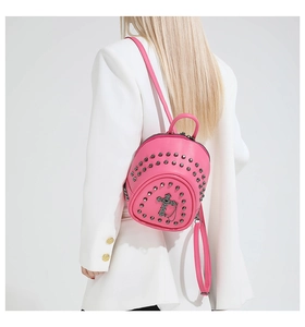 Vue détaillée du mini sac à dos punk rose avec rivets et croix gothique sur manteau blanc