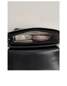 Top-down view of black piano crossbody bag interior with zipper pocket and daily essentials
