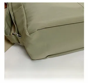 Close-up of precise stitching and durable metal D-ring on a green nylon backpack