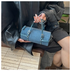 Detail of a mini blue cylinder bag with silver buckles and smooth leather handles