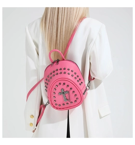 Gros plan d'un mini sac à dos punk rose avec rivets et croix en métal porté par un modèle