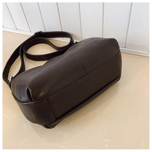 Vue détaillée du sac cabas en cuir marron foncé montrant la texture et les boucles en argent