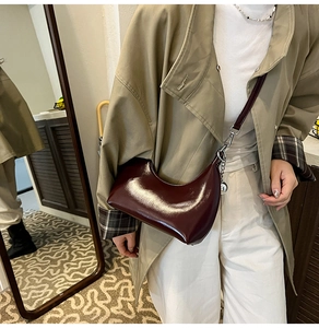 Detail of burgundy glossy leather crescent shoulder bag with silver zipper and slim strap