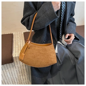 Caramel suede hobo bag on shoulder, paired with a gray herringbone wool coat in a classic style