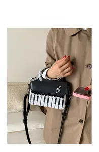 Detail of piano-themed crossbody bag with music notes and lace on khaki trench coat