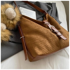 Gros plan sur la texture tressée marron d'un sac en daim avec boucle métallique élégante