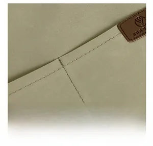 Detail view of water-resistant green nylon fabric with premium stitched leather logo patch