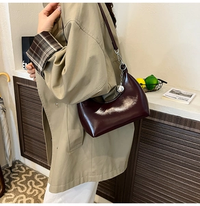 Detail of burgundy patent leather hobo bag featuring gloss finish and silver ball charm