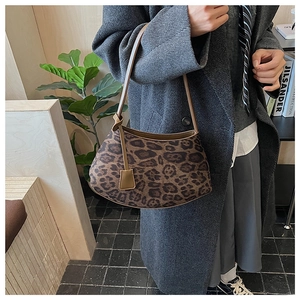 Detail of leopard print shoulder bag with knotted leather strap on a wooden surface