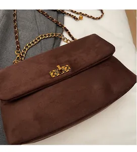 Close-up of brown suede shoulder bag with gold chain strap and vintage metal buckle