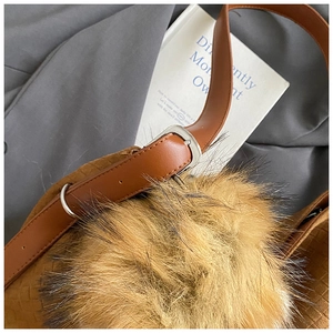Détail du sac cabas tressé en suédine marron avec pompon en peluche et boucle