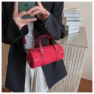 Detail of red cylinder barrel bag featuring matte texture and silver metal buckles