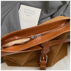 Gros plan sur un sac cabas tressé marron avec fermeture éclair argentée et détails en cuir