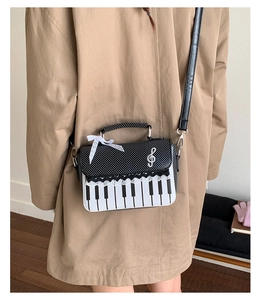 Close-up of piano keyboard handbag featuring lace trim and silk bow on a trench coat