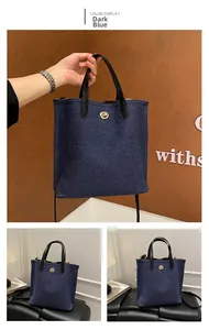Vue détaillée du sac cabas en denim bleu foncé avec fermoir doré et poignées en cuir