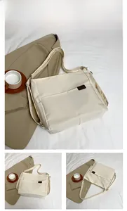 Detail view of a white waterproof nylon crossbody bag with brown leather brand label
