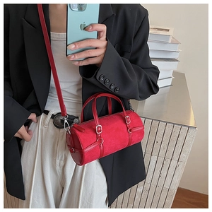 Detail of red cylindrical bag with matte texture, silver hardware and handle