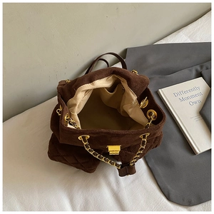 Makroansicht der braunen Wildleder-Beuteltasche mit Rautensteppung und goldener Kettenschulter