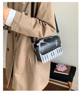 Detail of piano themed crossbody bag with musical note accents on khaki coat
