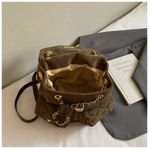 Detail eines dunkelbraunen Wildlederrucksacks mit Goldkette und gesteppten Pattentaschen