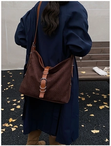 Détail d'un sac cabas tressé marron foncé avec anneau argenté et lanière en cuir