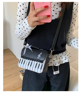 Detail of piano keyboard print and lace trim on a stylish crossbody bag worn by model