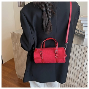 Detailed view of a red cylindrical Boston bag in faux suede with silver hardware