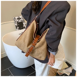 Détail du sac cabas vintage en daim marron avec lanières en cuir sur une tenue chic