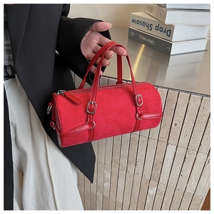 Detail of red cylindrical shoulder bag with silver buckle and suede texture