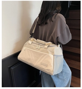 Close-up of beige waterproof travel bag with reinforced handles and multiple pockets