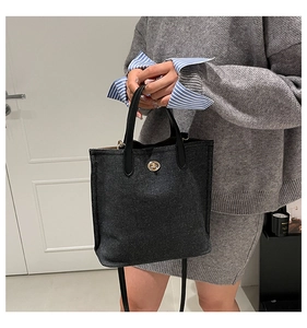 Détail du sac cabas en denim gris foncé avec fermoir doré et poignées noires élégantes