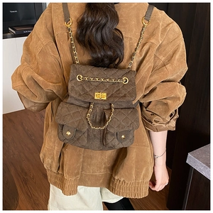 Detail eines dunkelbraunen gesteppten Wildlederrucksacks mit goldenen Ketten