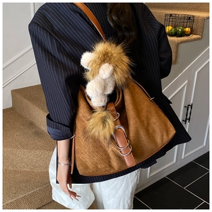 Détail du cabas en daim marron avec texture tissée, boucle en cuir et peluche de lion