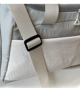 Detail of adjustable off-white nylon strap and two-tone lightweight travel bag fabric