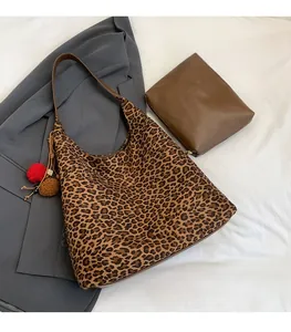 Detail of leopard print tote bag with brown strap and plush pompom charm accessory