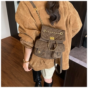 Gesteppter brauner Wildleder-Rucksack mit Goldketten und Drehverschluss am Model