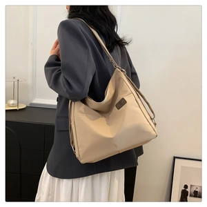 Detail of adjustable strap and minimalist logo on beige waterproof nylon tote bag