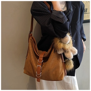 Détail du sac cabas en daim marron avec texture tissée et breloque lion en peluche