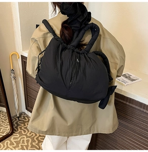 Rear view of model carrying a black quilted puffer tote bag with padded handles