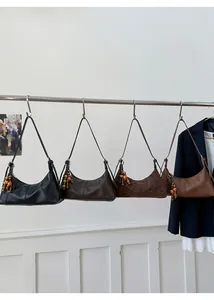 Detail von vier Retro-Baguette-Taschen in Schwarz, Braun und Leopard mit Holzperlenanhängern