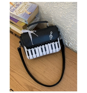 Detail of piano key pattern crossbody bag with lace bow and treble clef hardware