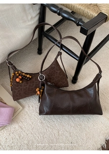 Detail of retro brown half-moon bags in leopard suede and glossy pleated leather