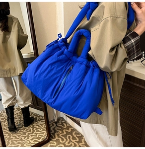 Close-up of puffy royal blue nylon tote bag with drawstring detail and thick handles